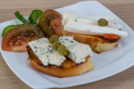 Tapas with soft blue cheese and black tomatoの写真素材