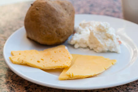 Ricotta and yellow cheeses with bun on breakfastの写真素材