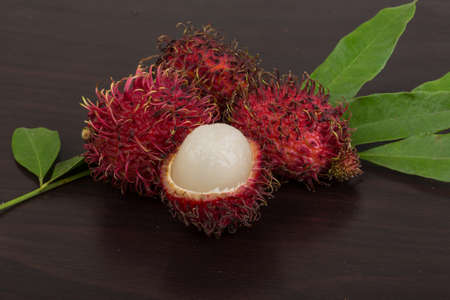 Fresh Rambutan with leaves on the wooden backgroundの写真素材