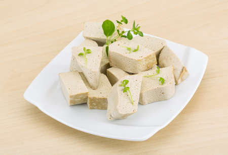 Tofu - soya cheese with herbs on the wood background