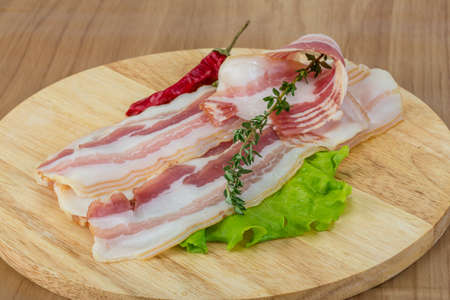 Bacon on the wooden background with salad leavesの写真素材
