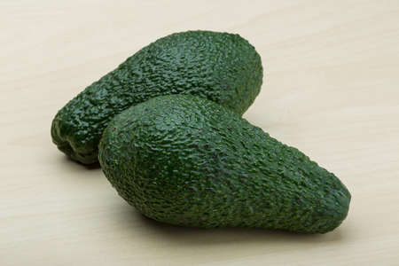 Fresh ripe green avocado on the wood background