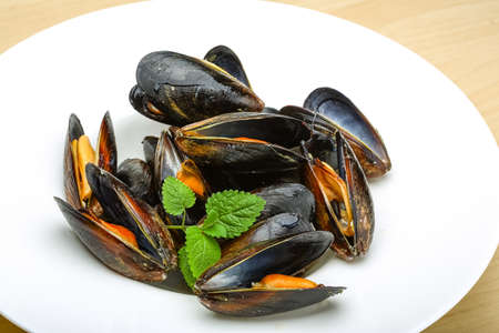 Fresh tasty Boiled mussels with herbs on wood background