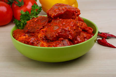 Raw marinated meat for bbq with herbs and spices on red tomato sauceの写真素材