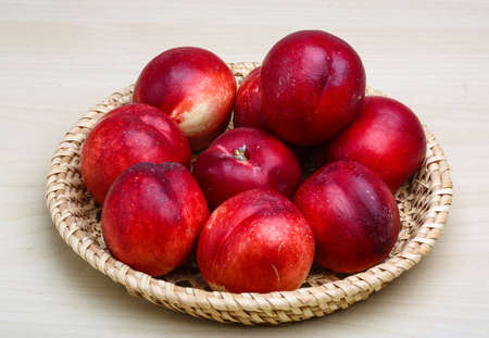 Fresh ripe Nectarines in the wooden plate
