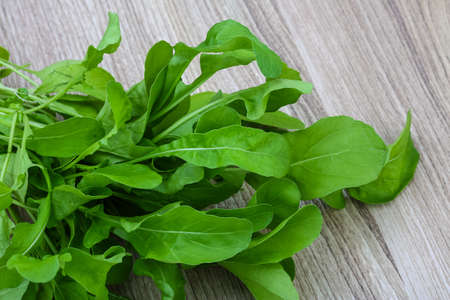 Fresh green Ruccola leaves heap on the wood backgroundの写真素材