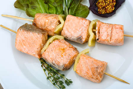 Salmon skewer with salad leaves, mustard and thymeの写真素材