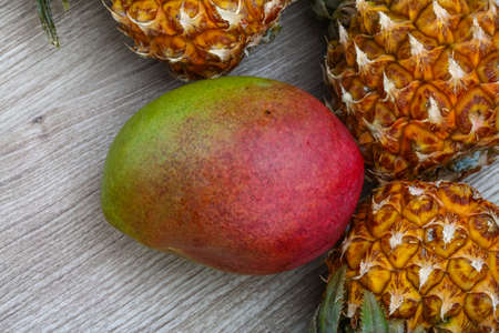 Mini pineapple and mango fruit on the wood backgroundの写真素材