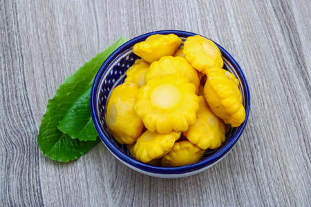 Pickled yellow patissons with salad leaves and fresh tomato