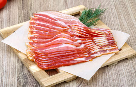 Fresh cold sliced bacon with dill branch on the wood backgroundの写真素材