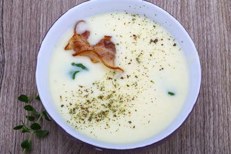 Cheese soup with bacon and herbs on the wood backgroundの写真素材