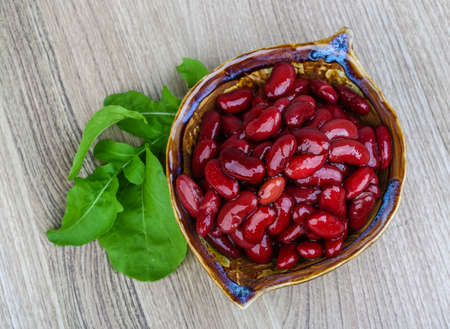 Kidney beans in the bowl with ruccola leaves on wood backgroundの写真素材