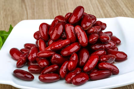 Kidney beans in the bowl with ruccola leaves on wood backgroundの写真素材
