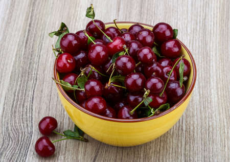 Fresh ripe Cherry in the bowl on wood backgroundの写真素材
