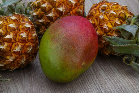 Mini pineapple and mango fruit on the wood backgroundの写真素材