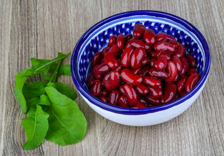 Kidney beans in the bowl with ruccola leaves on wood backgroundの写真素材