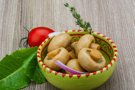 Pickled champignon with thyme on the wood backgroundの写真素材