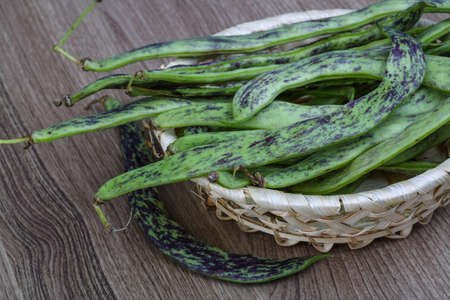 Raw green beans in the basket on the wood backgroundの写真素材