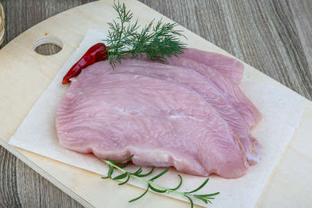Raw turkey breast steak with dill and rosemary on the wood backgroundの写真素材