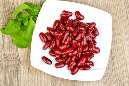 Kidney beans in the bowl with ruccola leaves on wood backgroundの写真素材