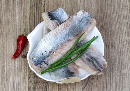 Herring fillet with green onion, basil leaves and pepper