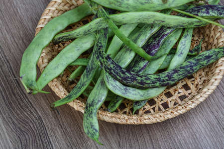 Raw green beans in the basket on the wood background
