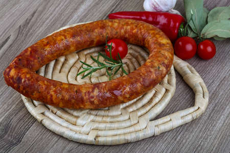 Sausage ring with cherry tomato and rosemary on the wood background