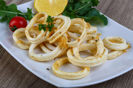 Fried squid rings with lemon, herbs and spicesの写真素材