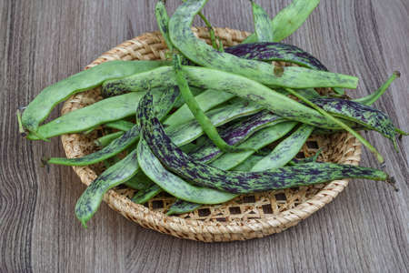 Raw green beans in the basket on the wood backgroundの写真素材