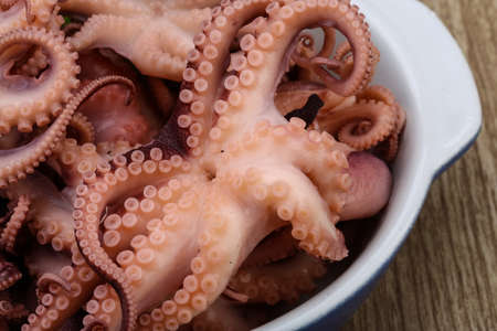 Marinated baby octopus in the bowl on wood background