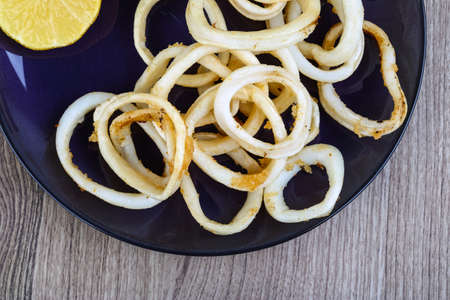 Fried squid rings with lemon, herbs and spicesの写真素材