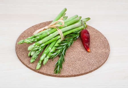 Raw asparagus heap with rosemary leaves on the wood backgroundの写真素材