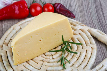 Yellow cheese triangle with rosemary herbs on the wood background