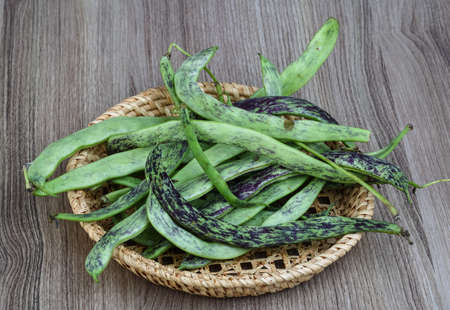 Raw green beans in the basket on the wood background