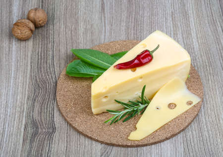 Triangle yellow cheese with rosemary, pepper and salad leavesの写真素材