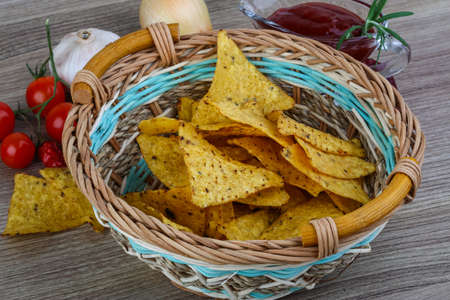 Nachos chips with tomato hot sauce on the wood backgroundの写真素材