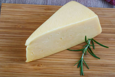 Yellow cheese triangle with rosemary herbs on the wood backgroundの写真素材