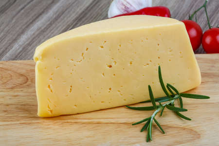 Yellow cheese triangle with rosemary herbs on the wood backgroundの写真素材