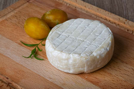 Round Brie cheese with yellow plums and estragonの写真素材