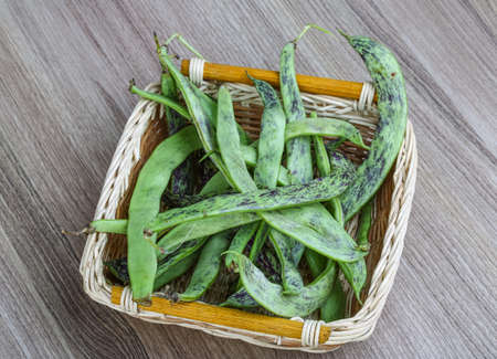 Raw green beans in the basket on the wood background