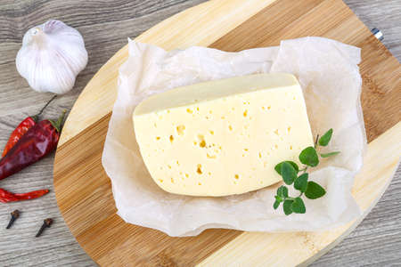 Part of round cheese on the wood background with herbsの写真素材