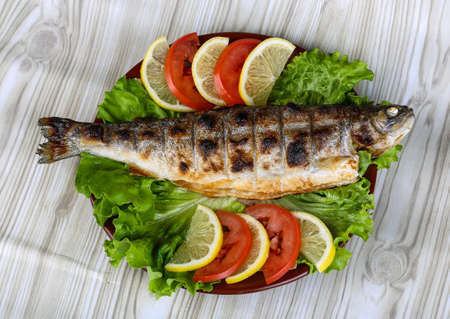 Grilled trout barbeque served lemon, tomato and salad leavesの写真素材