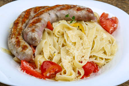 Grilled sausages with pasta on the wood backgroundの写真素材