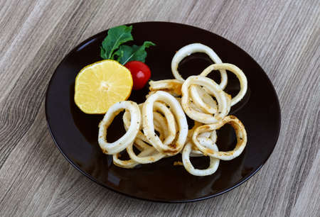 Fried squid rings with lemon, herbs and spicesの写真素材