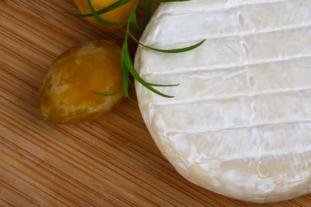 Round Brie cheese with yellow plums and estragon