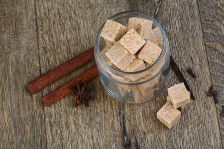 Brown sugar with cinnamon and clove seeds on the wood