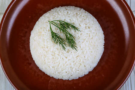 Hot Steamed rice with dill branch on the brown plateの写真素材