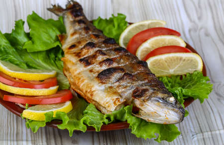 Grilled trout barbeque served lemon, tomato and salad leaves