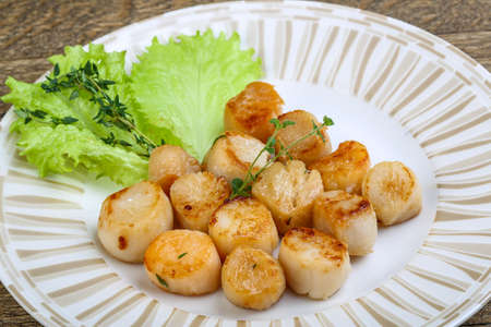 Baked scallops with sauce served salad leaves and thymeの写真素材