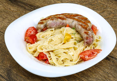 Grilled sausages with pasta on the wood backgroundの写真素材